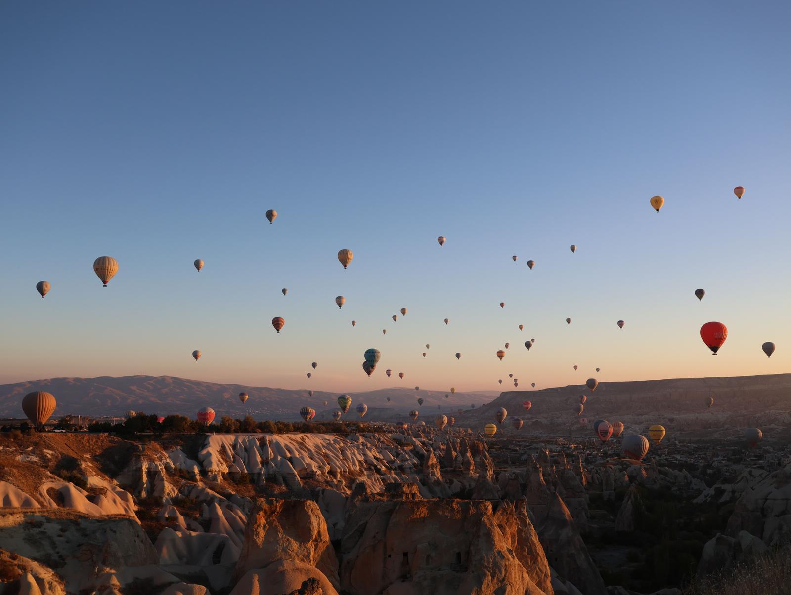 Hot air balloons rising over the Cappadocia valleys at dawn