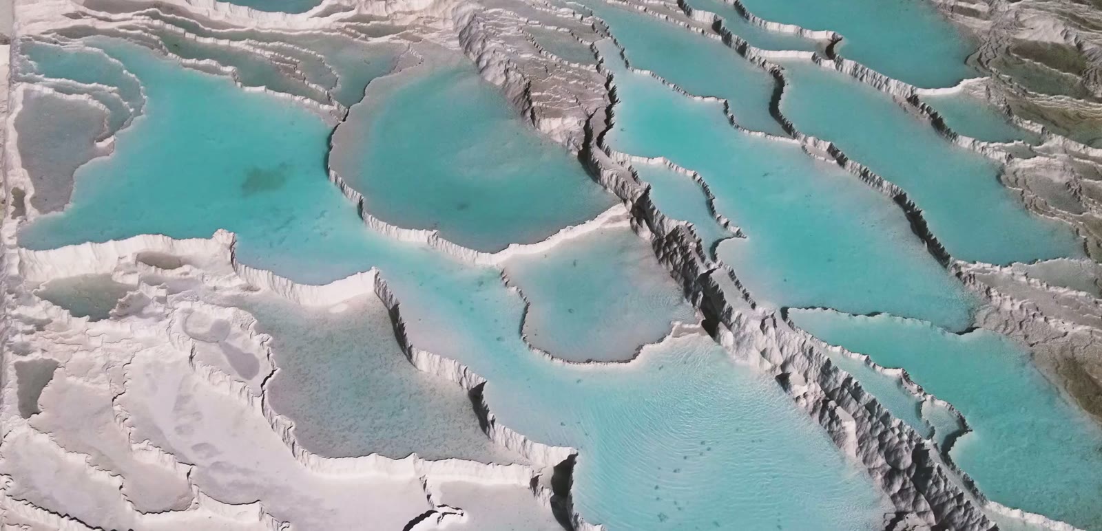 Hot air balloons over the white travertine terraces of Pamukkale at dawn