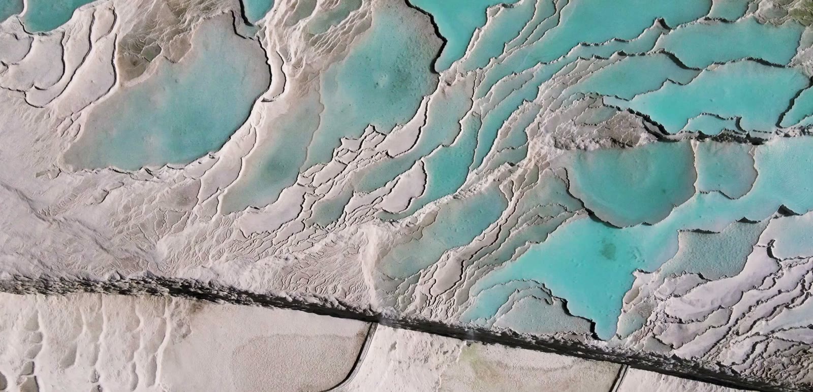 Thermal spring water running in a thin sheet over the white travertine surface at Pamukkale